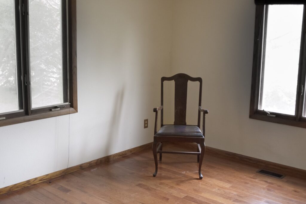 A lone chair in an empty room: how stuck and lonely it feels when you're measuring the next breath as it comes.
